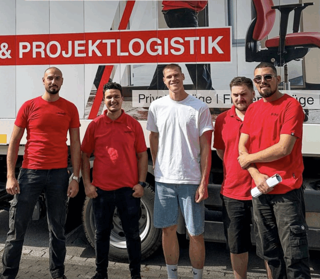 Umzugsmitarbeiter mit Promifu0baller Tigges vor einem Umzugstransporter der Firma Hartmann International